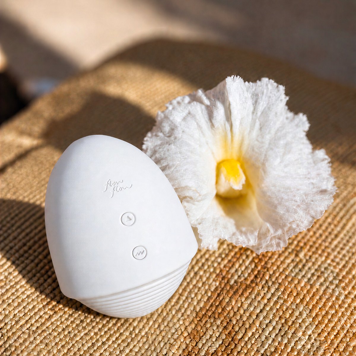 Small egg-shaped Pépite warming suction toy next to a white flower