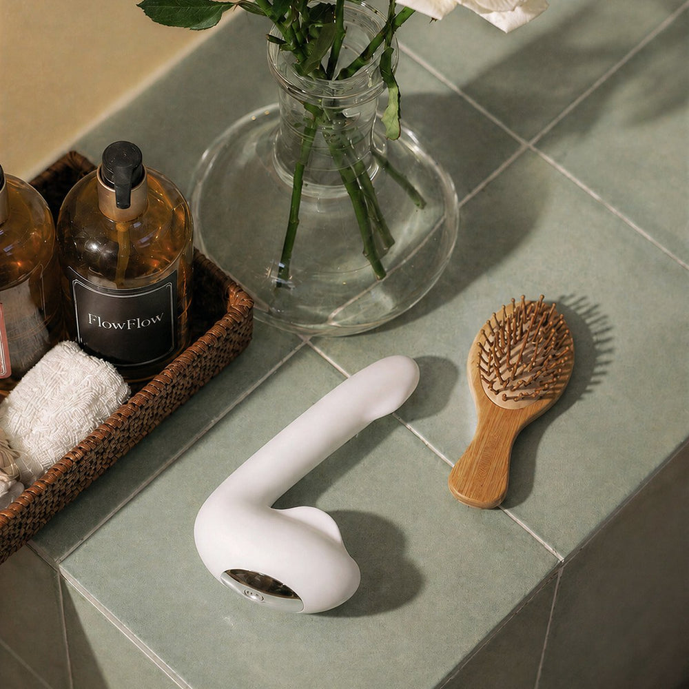 Plume vibrator on a bathroom shelf among flowers and toiletries